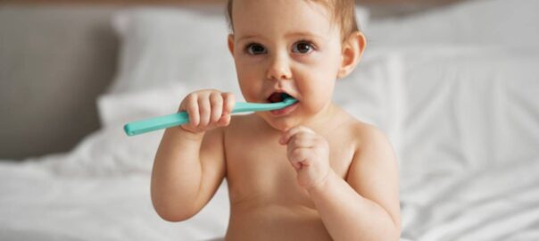 Little baby starting brushing a teeth after the bath.