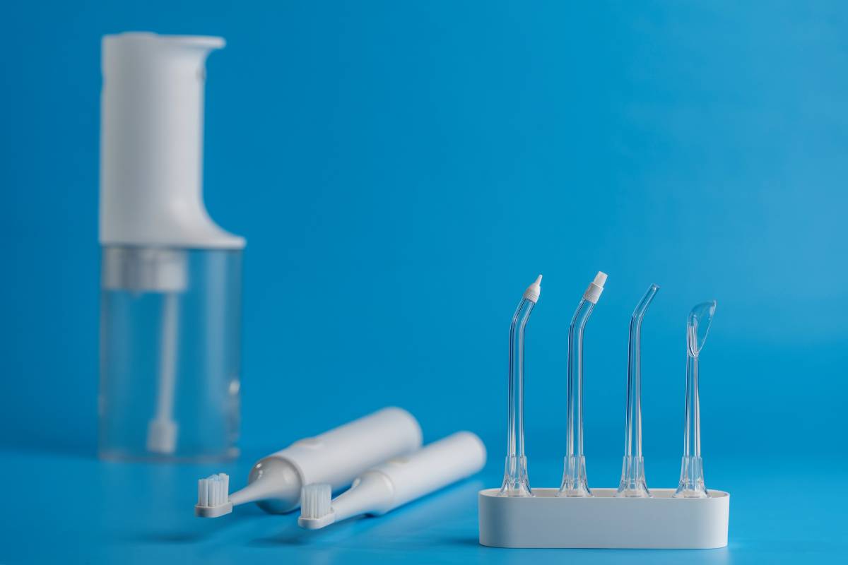 Portable oral dental flosser with different attachments and white electric toothbrushes on blue background.