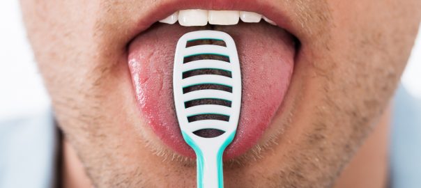Close-up of man brushing his tongue - should you be brushing your tongue?