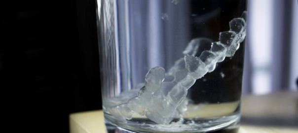Invisalign tray suspended in clear water solution in glass