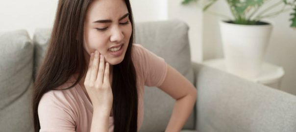 Woman holding hand against jaw, pained expression