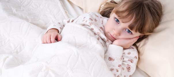 Toddler girl holding cheek in bed